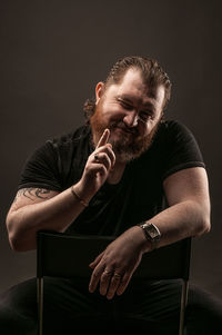 Young man sitting against black background