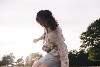 Young woman with camera standing at park