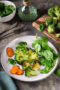 Grilled broccoli and carrots and fresh spinach leaves on a plate. vegetable diet. vertical view