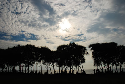 Silhouette trees on field against sky at sunset