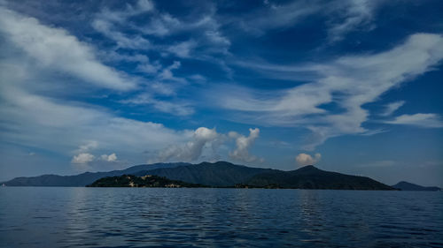 Scenic view of sea by mountains against sky