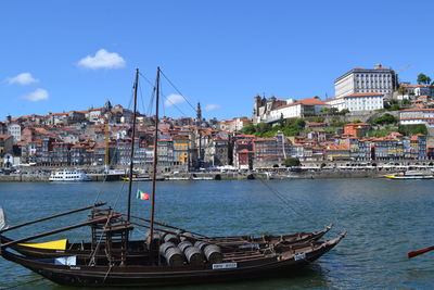 Boats in river by city against sky