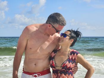 Happily married diversified couple hugging at florida beach in summertime.