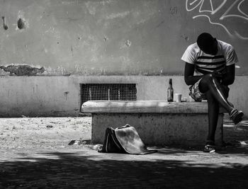 Rear view of man sitting on wall