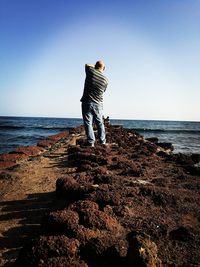 Rear view of man standing on rock at beach