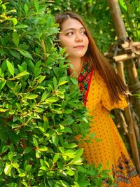 Portrait of young woman standing against plants