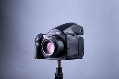 Close-up of digital camera on tripod against gray background