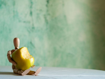 Close-up of apple on table against wall