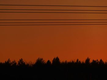 Silhouette trees against orange sky