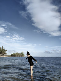 Rear view of woman standing on sea against sky