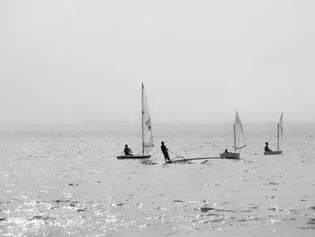 People on sailboat in sea against sky