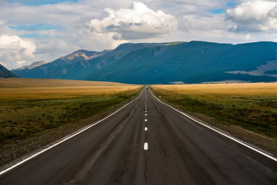 Empty road leading towards mountains against sky