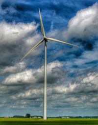 Low angle view of wind turbines on field against sky