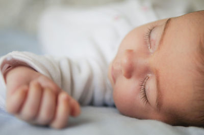 Close-up of cute baby girl sleeping on bed at home