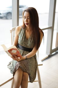 Woman reading book while sitting at home