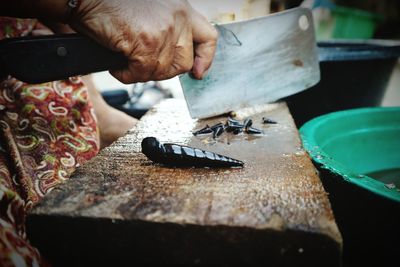 Midsection of woman cutting seashell at fish market