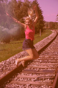 Full length of woman jumping on railroad track