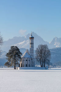 Lighthouse on snow covered landscape against sky