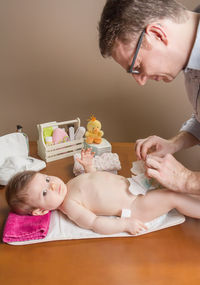 Man changing diaper of baby girl at home