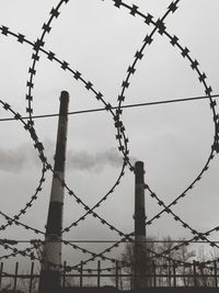 Low angle view of barbed wire against sky