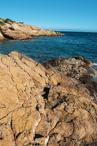 Scenic view of rocks on beach against clear sky