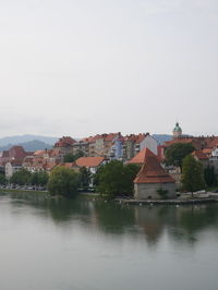 Houses by lake against sky in city