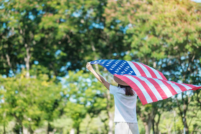 Flag holding umbrella against trees