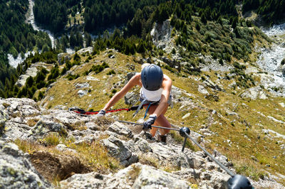 Full length of woman climbing rocks in a mountain at heini-holzer-klettersteig