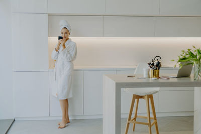 Young woman applying moisturizer on face at home