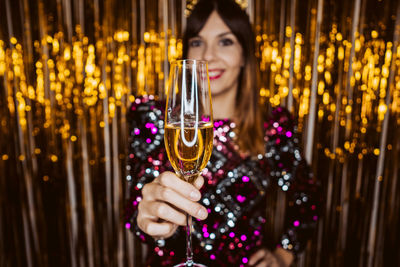 Portrait of smiling young woman with champagne against decorations