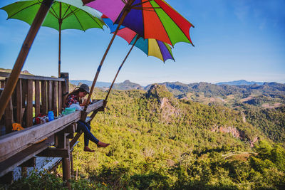 Woman sitting on mountain against sky