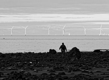 Man with umbrella on beach against sky