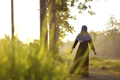 Rear view of woman standing on field