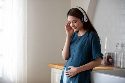 Young woman looking away while standing at home