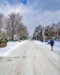 People walking on snowy road against sky