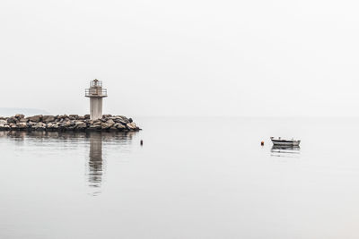 Lighthouse by lake against clear sky