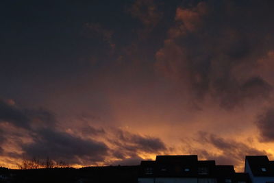 Low angle view of silhouette buildings against dramatic sky