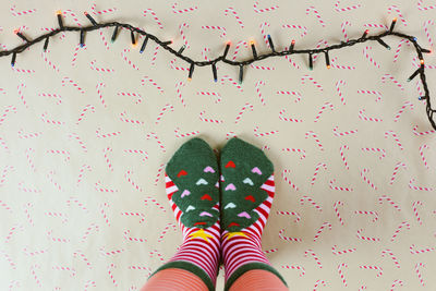 Low section of person wearing sock standing by string light and decorations