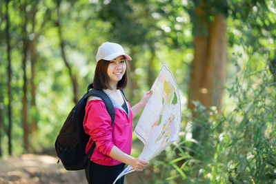 Smiling young woman standing by tree