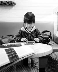 Boy using digital tablet while sitting on sofa at home