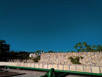 Trees and buildings against clear blue sky