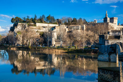 Reflection of trees and buildings in lake against blue sky