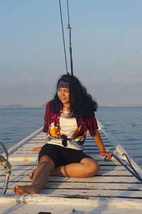 Young woman sitting on boat against sea against sky