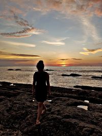 Rear view of man standing on beach during sunset