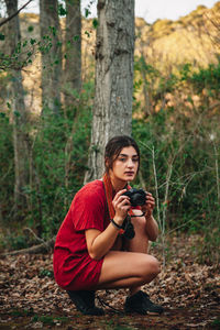 Young woman photographing in forest