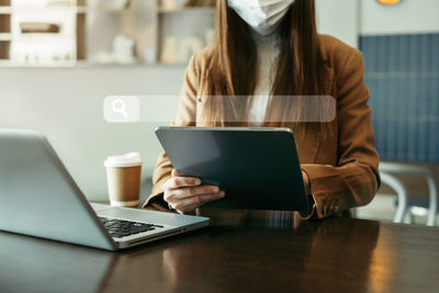 Midsection of woman using laptop at table