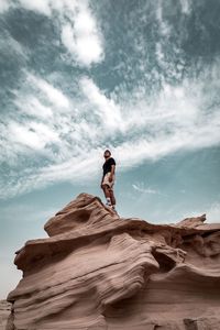 Man standing on rock against sky