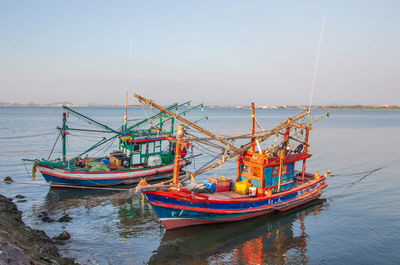 Colorful fishing boats are securely tied down directly at the pier with seaman's ropes and knots