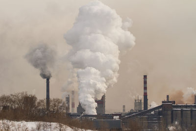 Smoke emitting from factory against sky