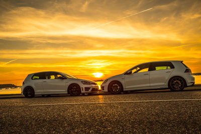Cars parked on road against orange sky